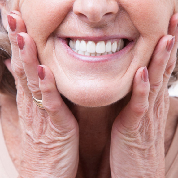 A woman smiling while wearing dentures