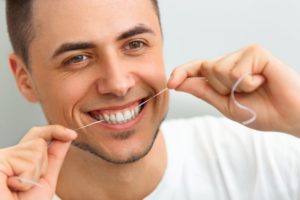 man smiling while flossing his teeth