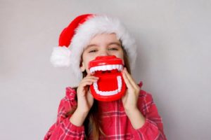 child wearing a santa hat and holding a model of a mouth