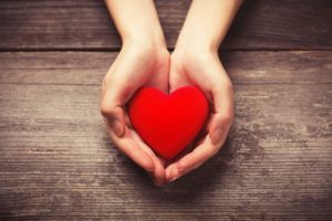 Cupped hands holding small red heart