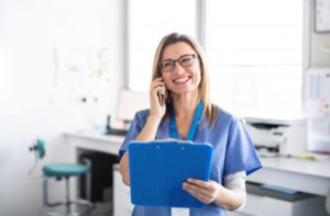 dentist in Midlothian smiling while talking on phone and holding blue clipboard 