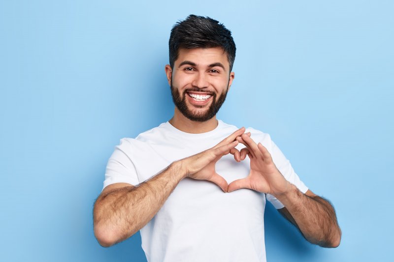 person smiling and making heart with fingers
