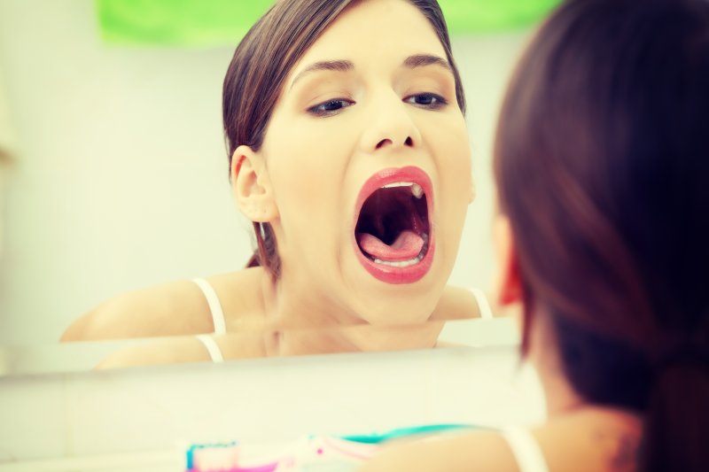 woman checking mouth for signs of oral cancer