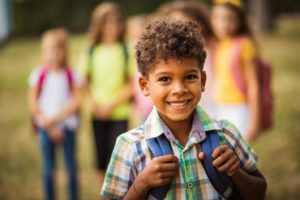 Young child smiling on his first day back to school.