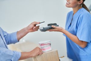 A patient paying for treatment at their dentist’s office in Midlothian