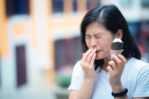 Woman experiencing tooth pain while eating ice cream