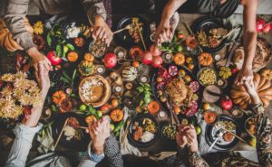 People holding hands over a table full of autumn harvest foods