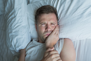 Man in bed with a toothache