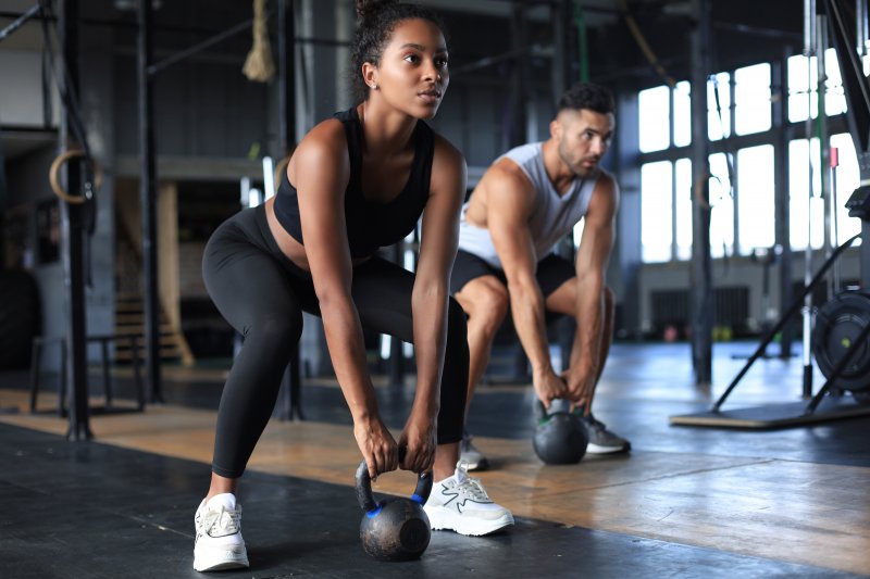 man and woman lifting weights in a gym