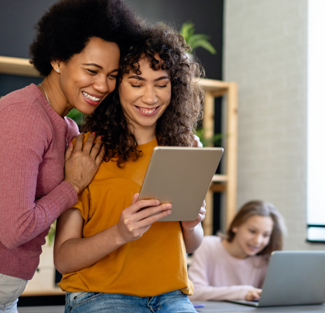 Mom and college-aged daughter smiling at tablet.
