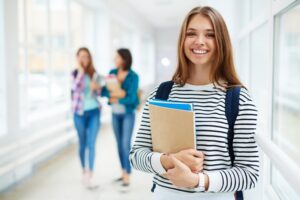 Student smiling with notes in her arms